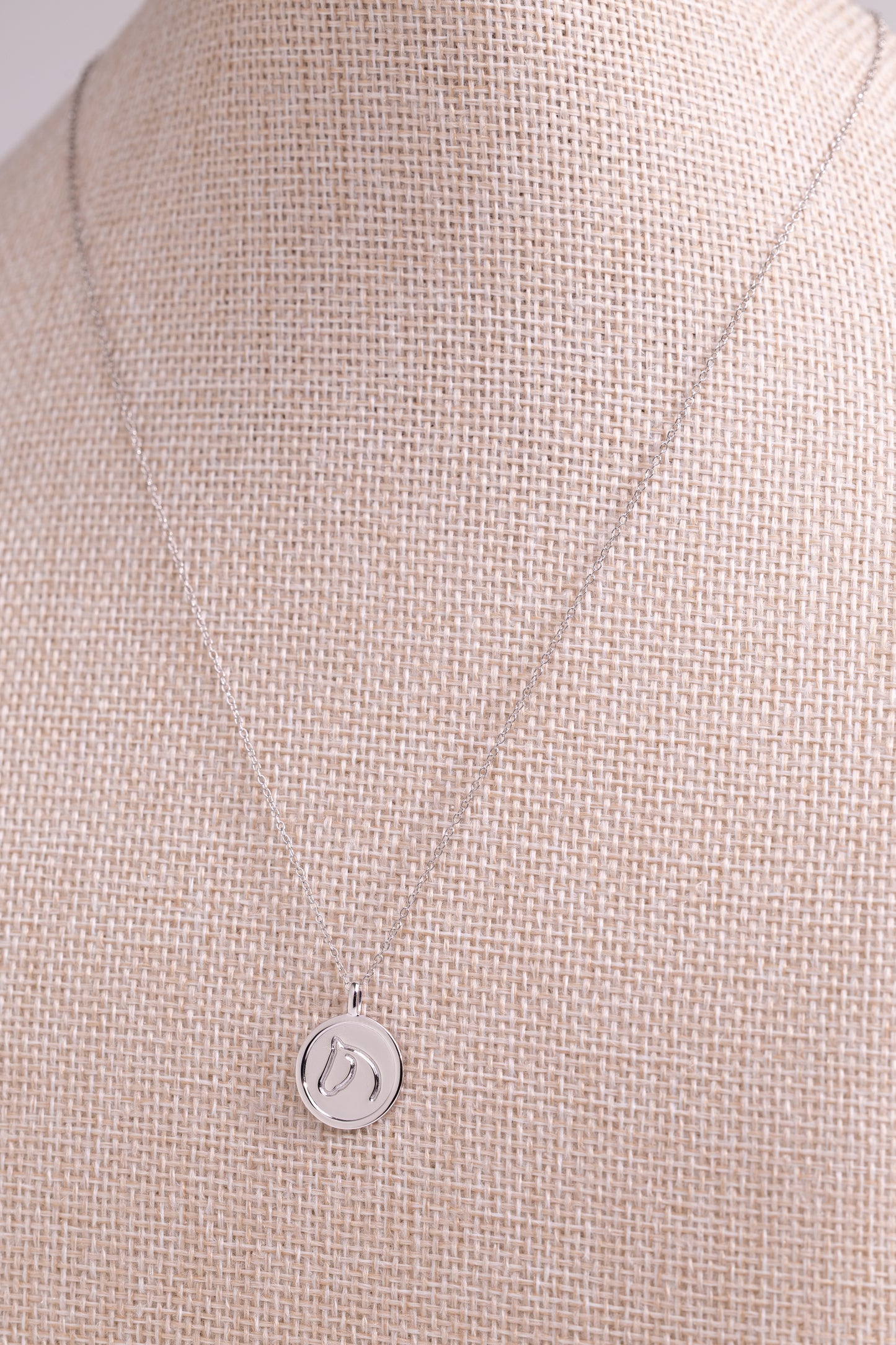 Sterling Silver pendant from The Gilded Horse, on a beige fabric background.
