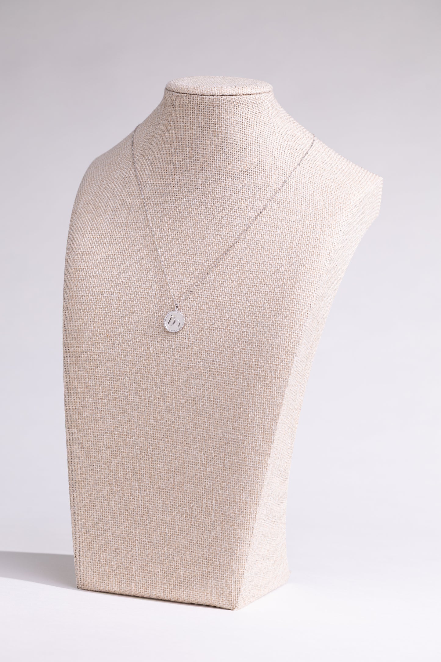 White gold TGH necklace with diamonds on a mannequin bust against a white background.