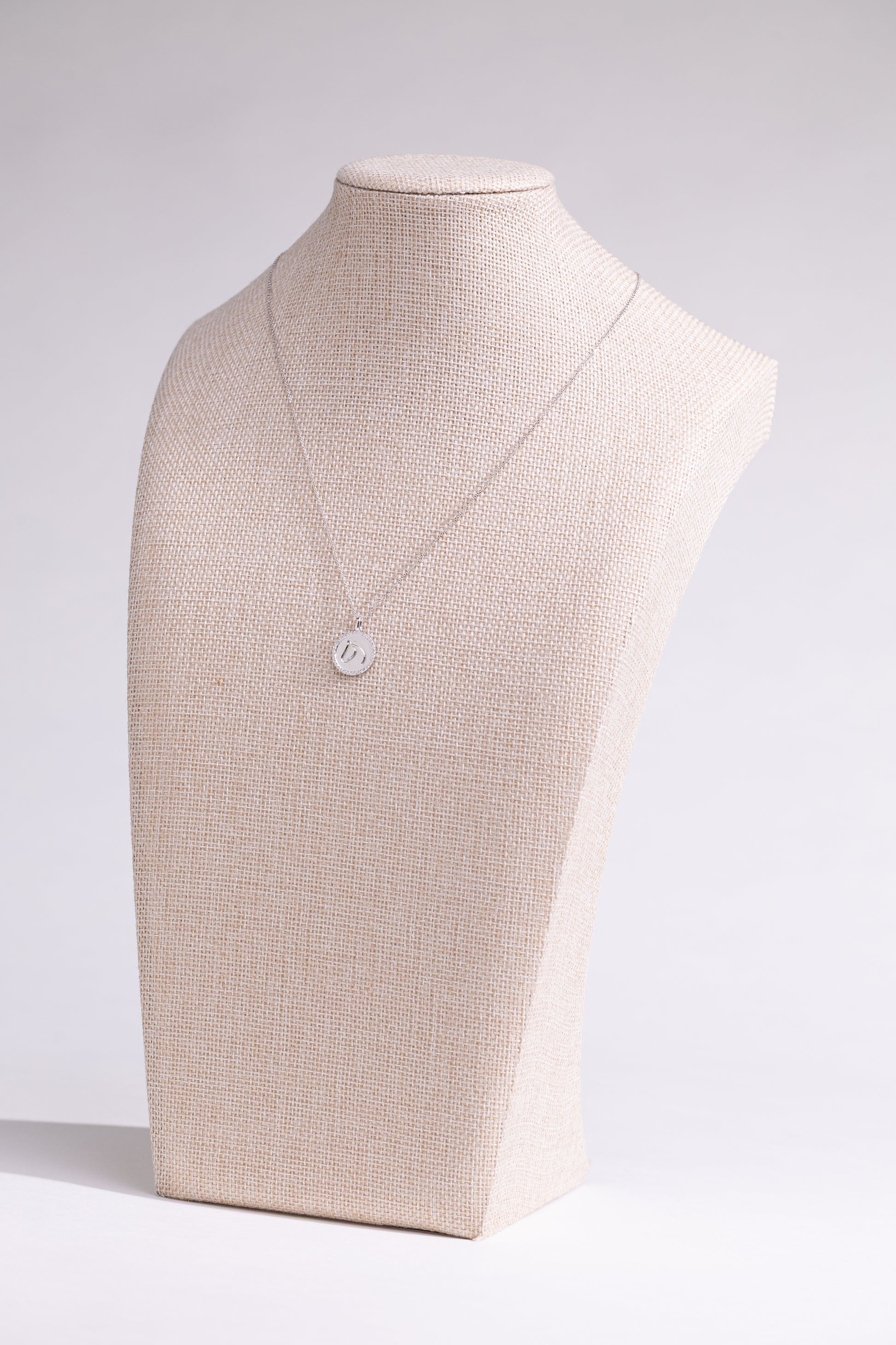 White gold TGH necklace with diamonds on a mannequin bust against a white background.