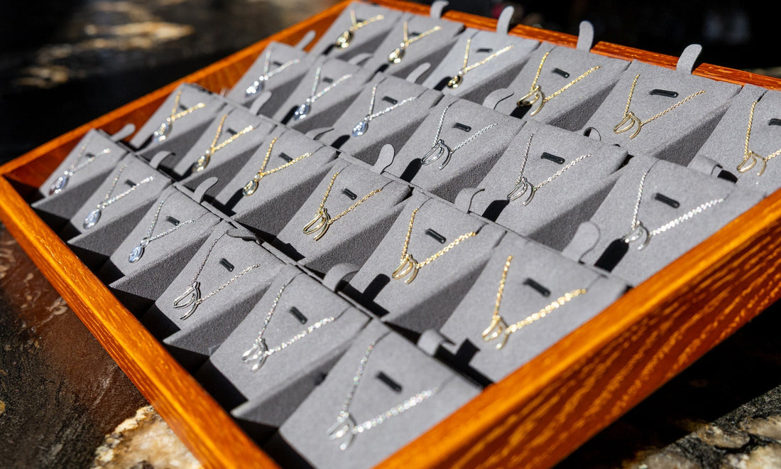 The Gilded Horse display tray of horse-head pendant necklaces in gold and silver
