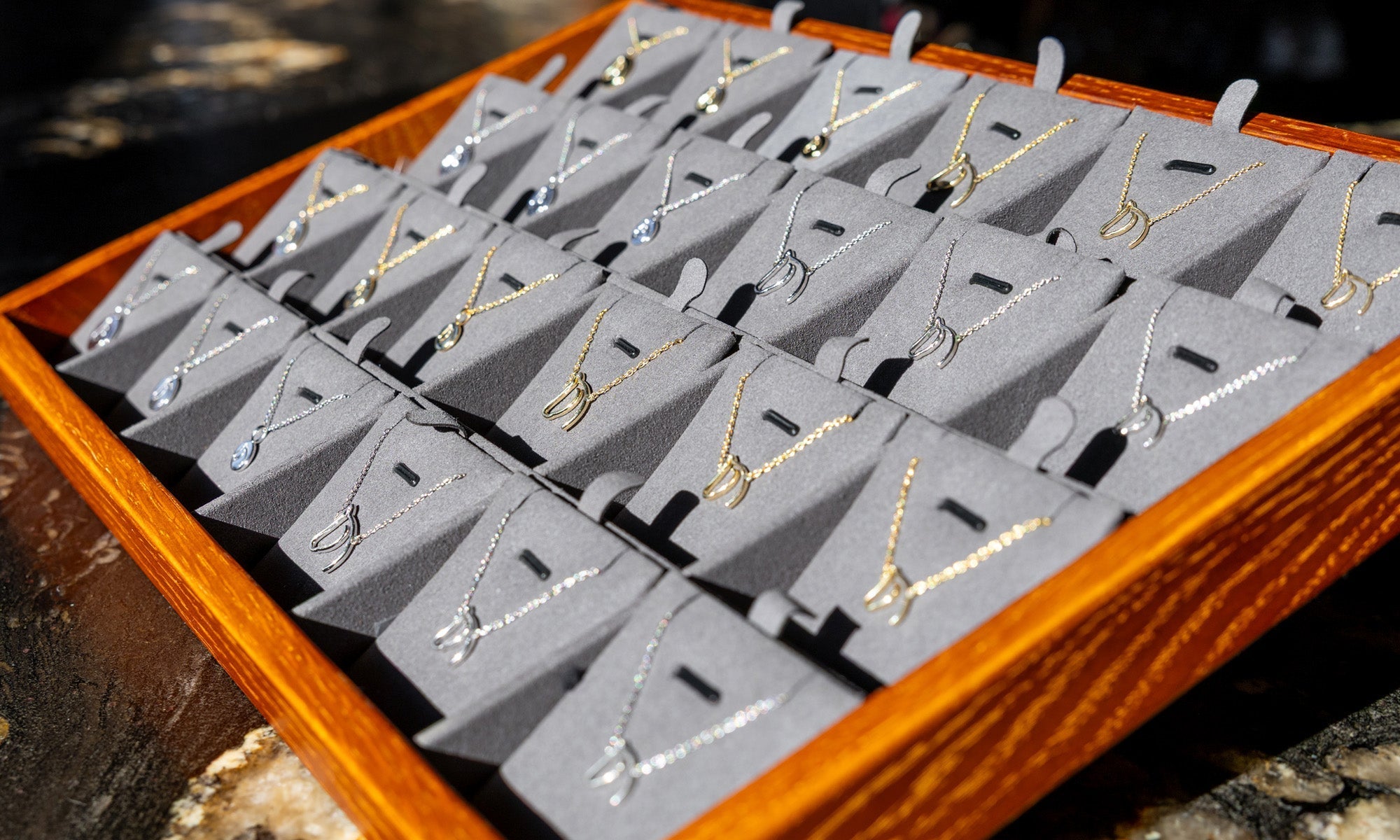 The Gilded Horse display tray of horse-head pendant necklaces in gold and silver