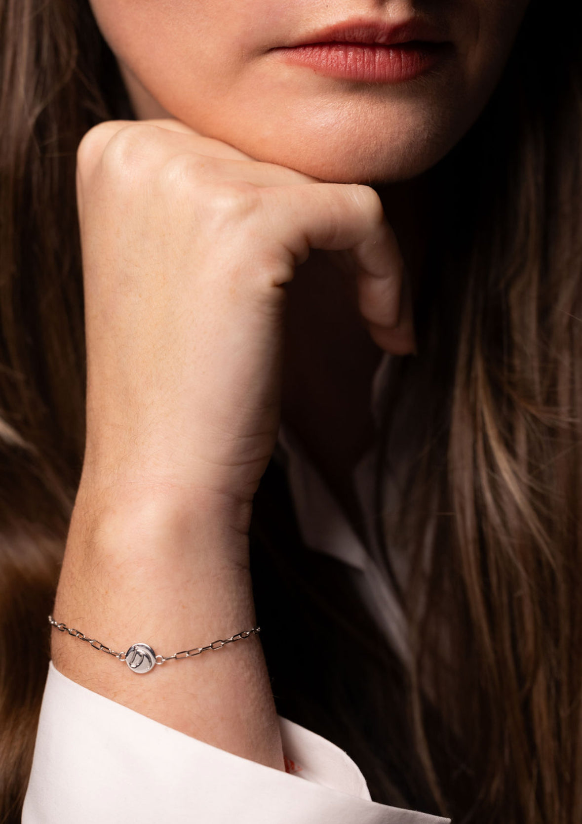 Woman resting her chin on her hand, wearing a silver-tone Circle Medallion horse bracelet