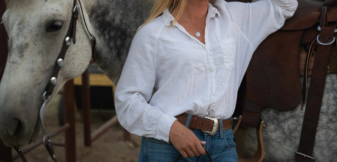 Woman in tailored blazer wearing a gold horse pendant necklace in equestrian style