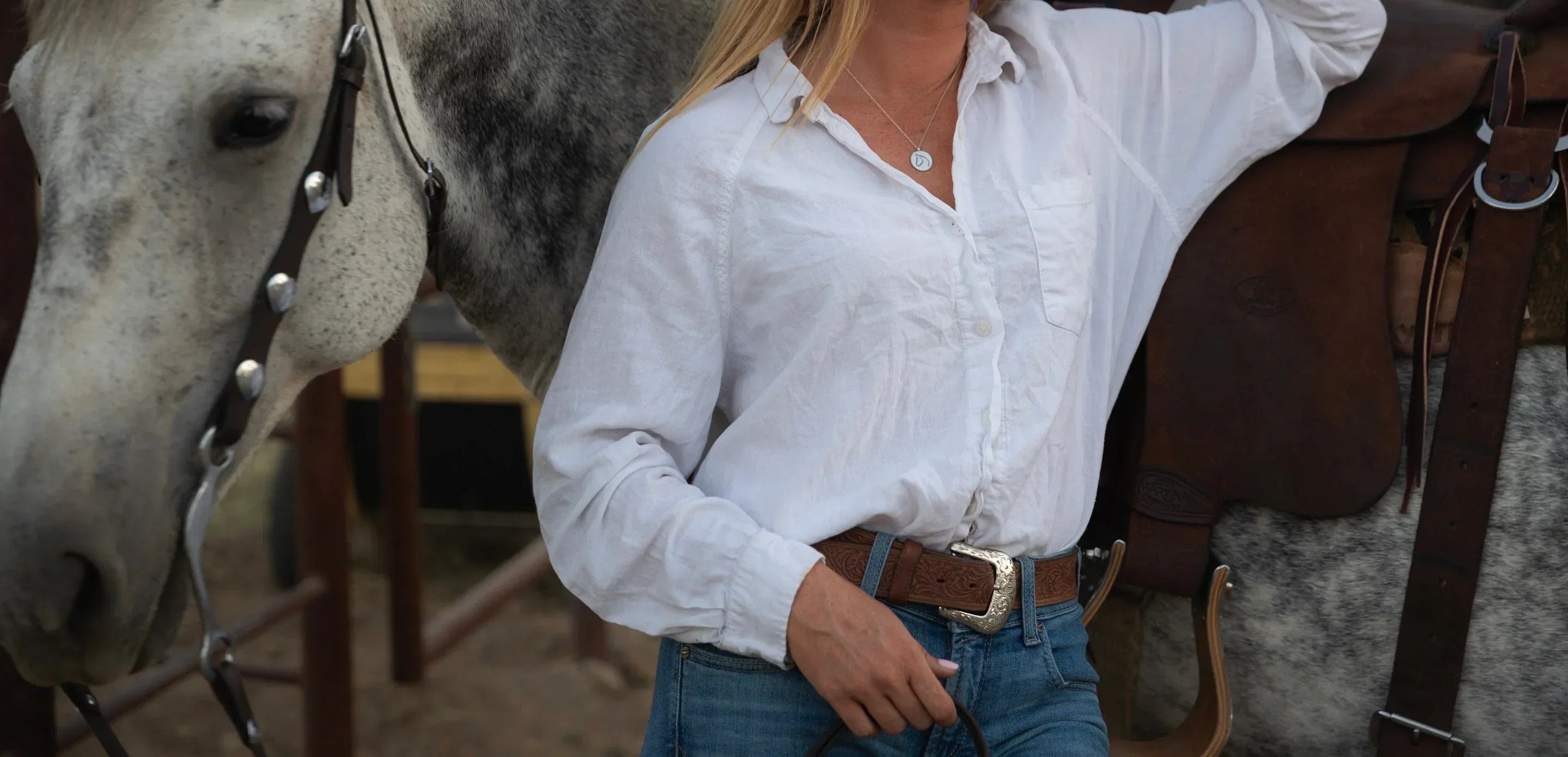 Woman in tailored blazer wearing a gold horse pendant necklace in equestrian style