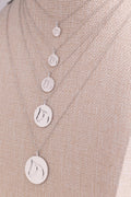 Five sterling silver circle medallion horse necklaces in graduated sizes on a beige bust