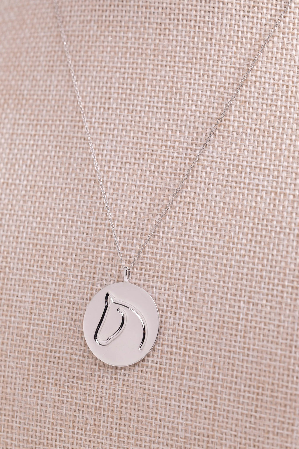 Single sterling silver circle medallion horse necklace displayed on a linen bust