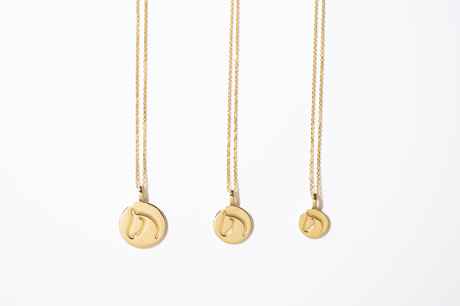 Three Gold Circle Medallion Pendant Necklaces from the The Gilded Horse (Large, Medium & Small) on a white background.