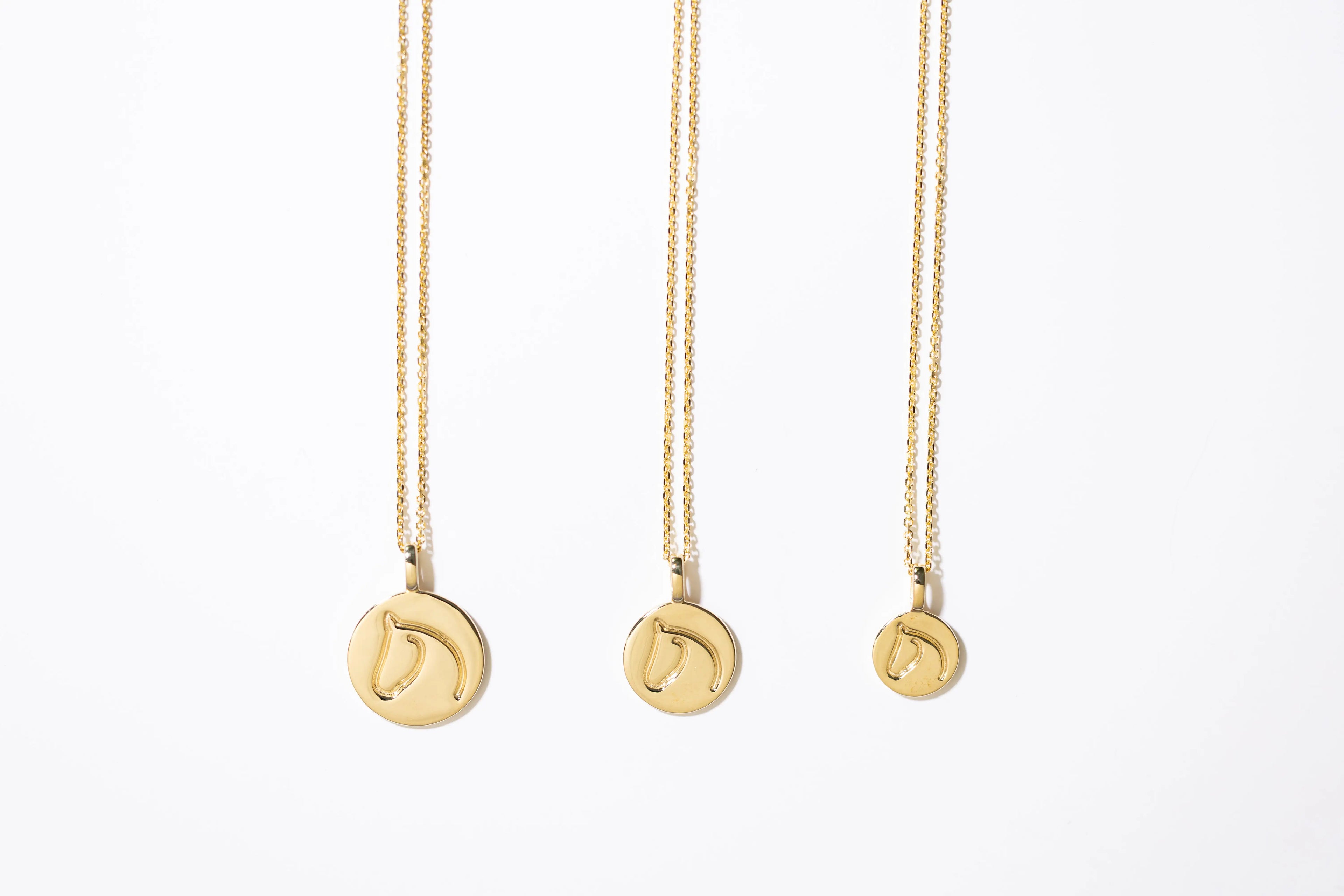 Three Gold Circle Medallion Pendant Necklaces from the The Gilded Horse (Large, Medium & Small) on a white background.