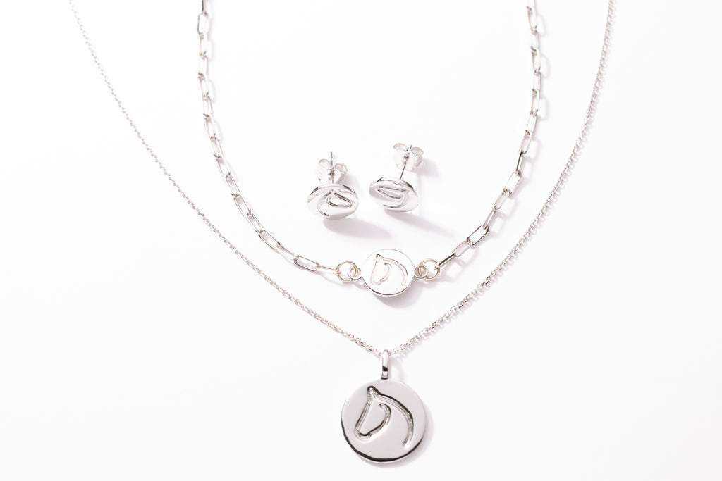 Silver necklace, bracelet and earrings set on a white background.