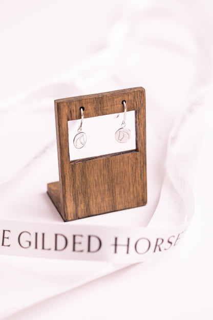Sterling silver earrings with The Gilded Horse logo on a wooden display stand with a white background.