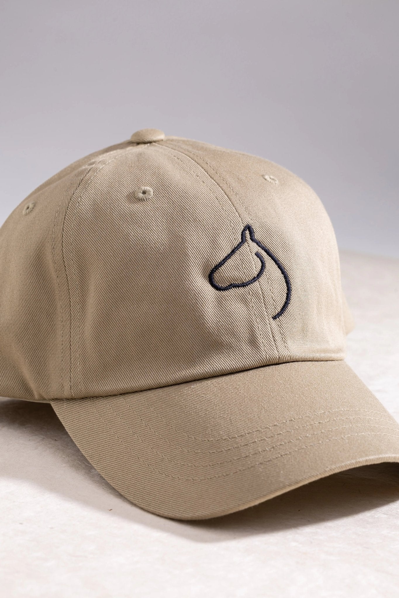 The Gilded Horse khaki dad hat with an embroidered horse-head logo, side angle