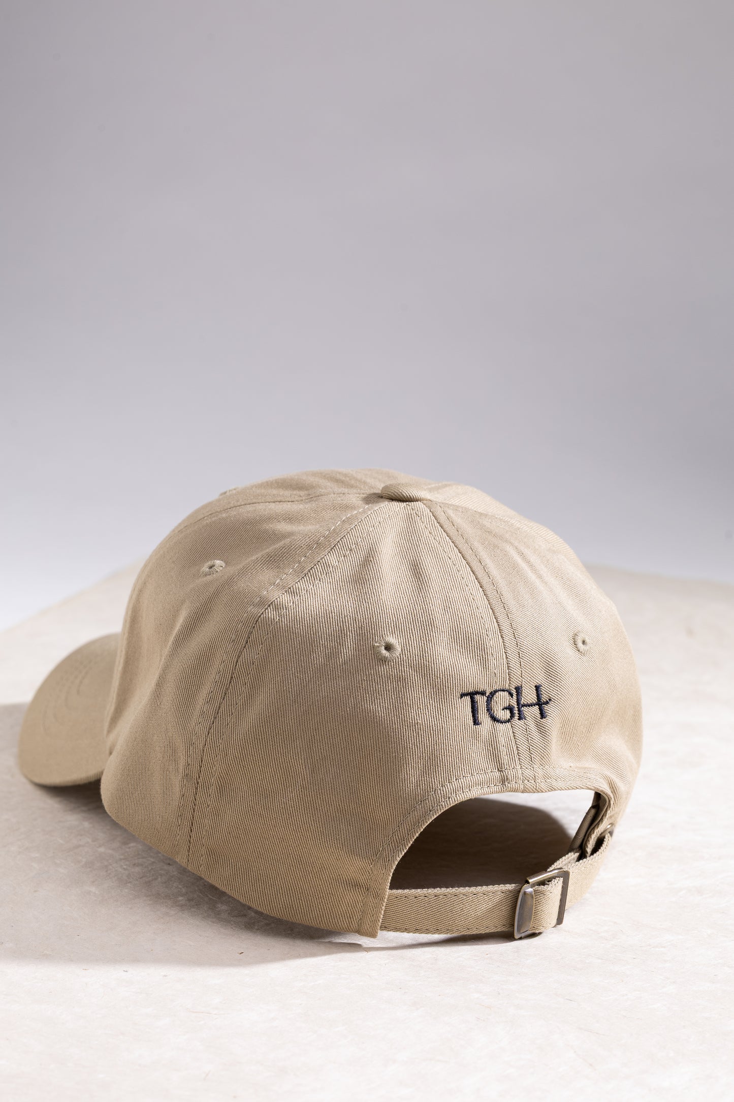 Beige cap with 'TGH' logo on a light gray background