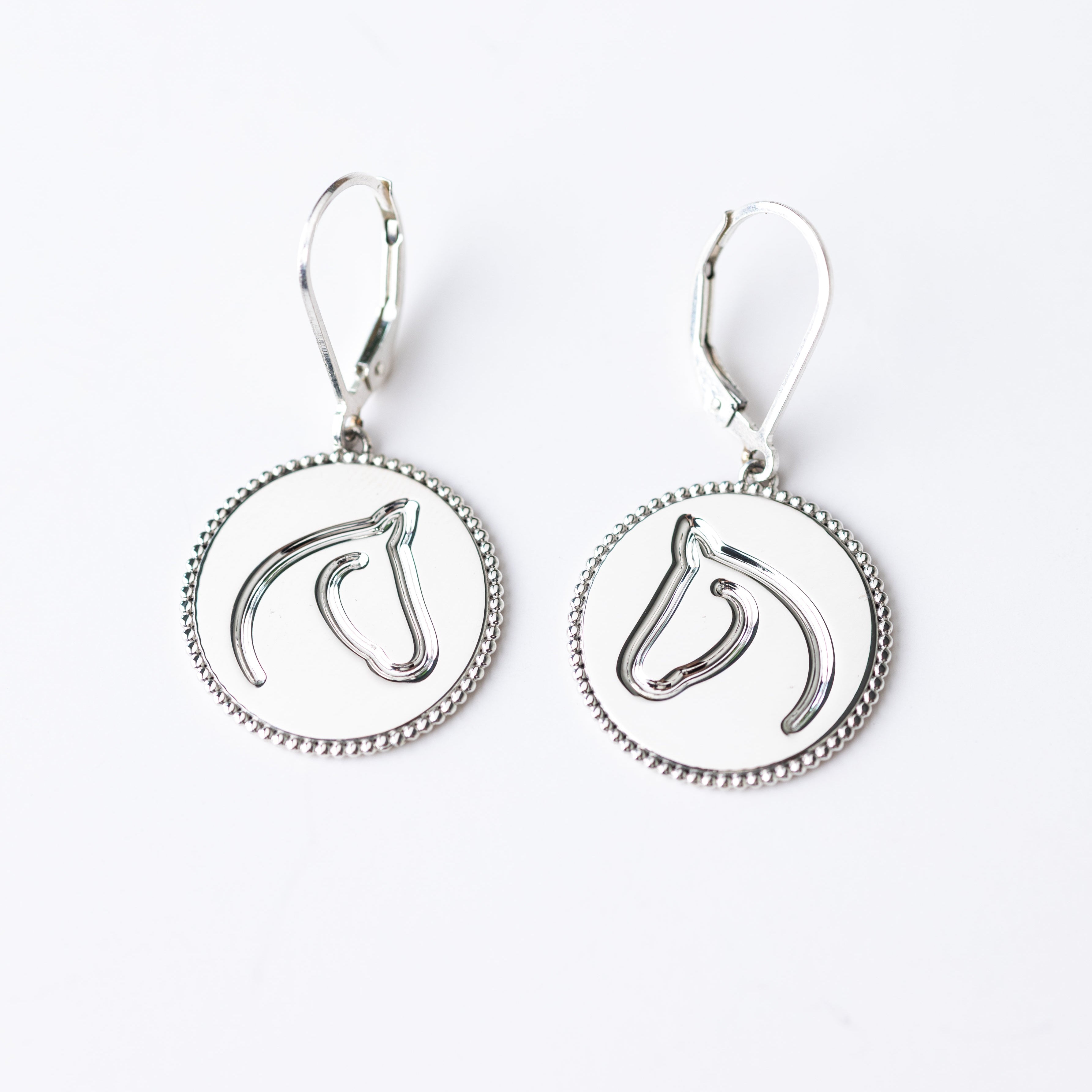 Pair of silver earrings with circular designs on a white background