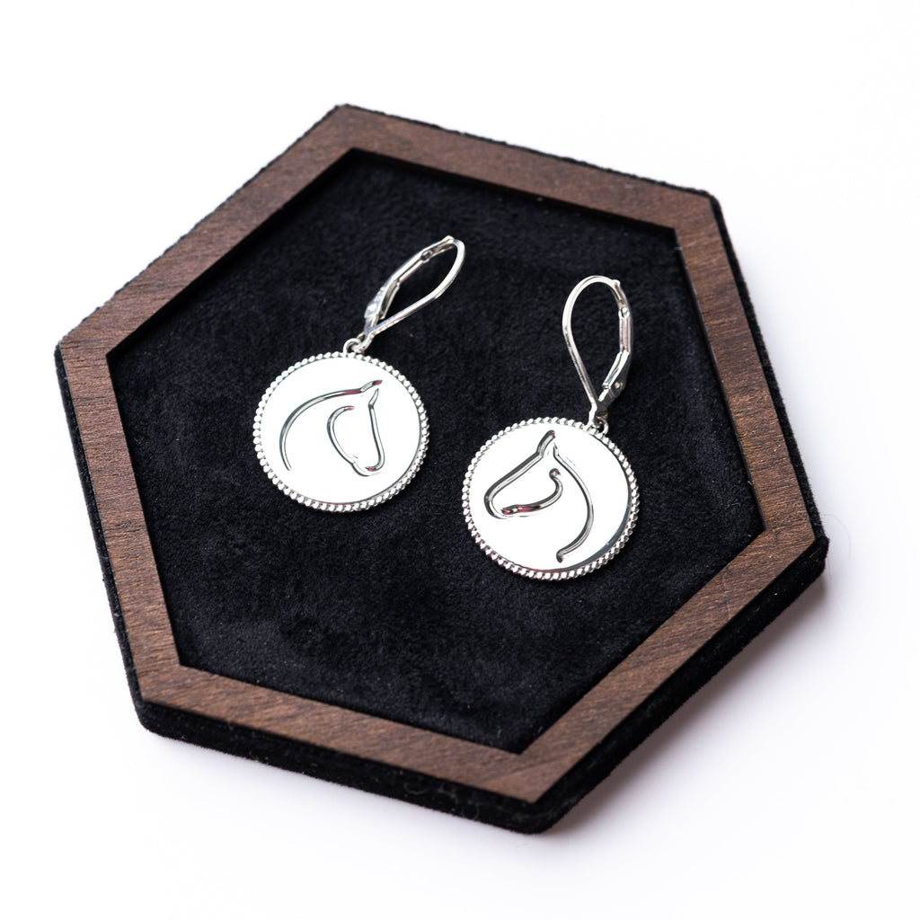 Silver earrings on a hexagonal wooden stand with black felt
