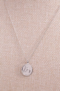 Sterling silver circle medallion horse necklace draped on beige woven fabric