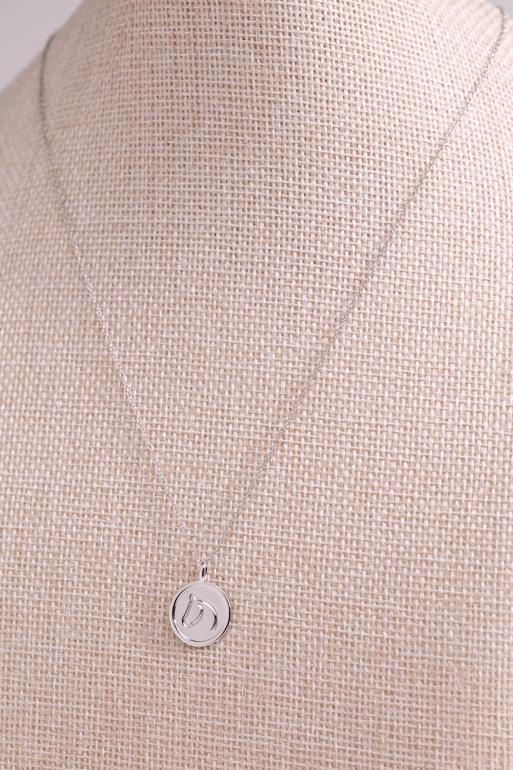 Sterling Silver pendant from The Gilded Horse, on a beige fabric background.