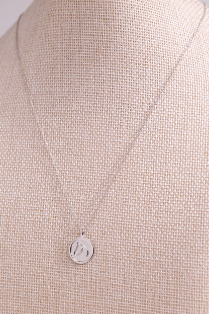 Sterling Silver pendant from The Gilded Horse, on a beige fabric background.