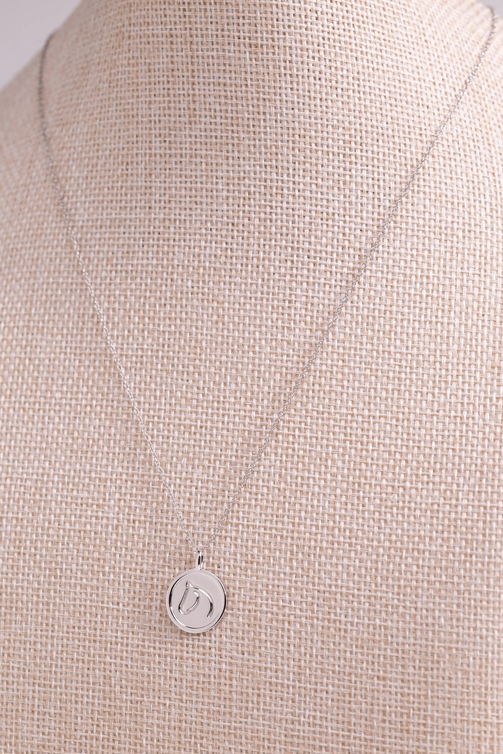 Sterling Silver pendant from The Gilded Horse, on a beige fabric background.