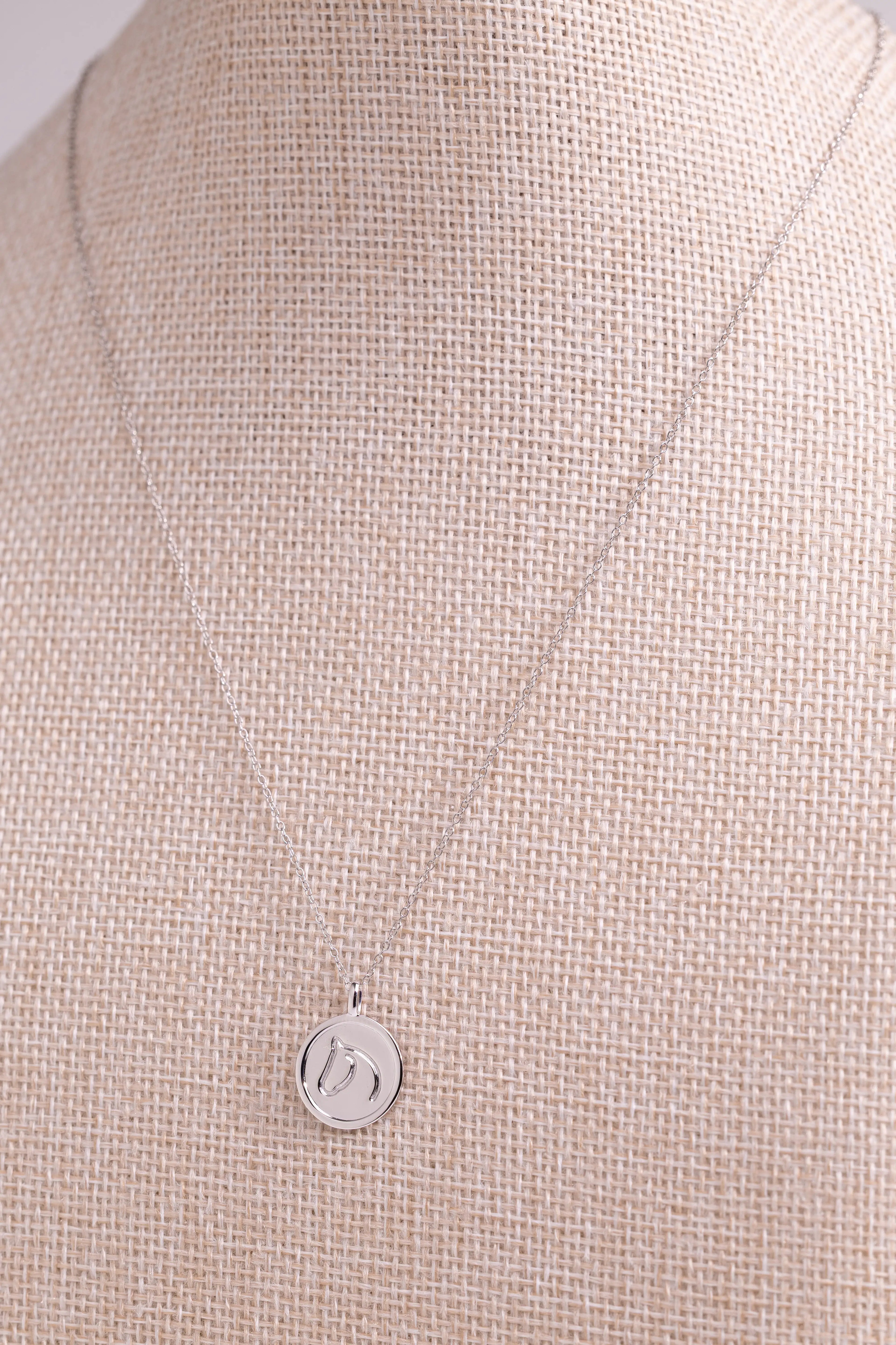 Sterling Silver pendant from The Gilded Horse, on a beige fabric background.