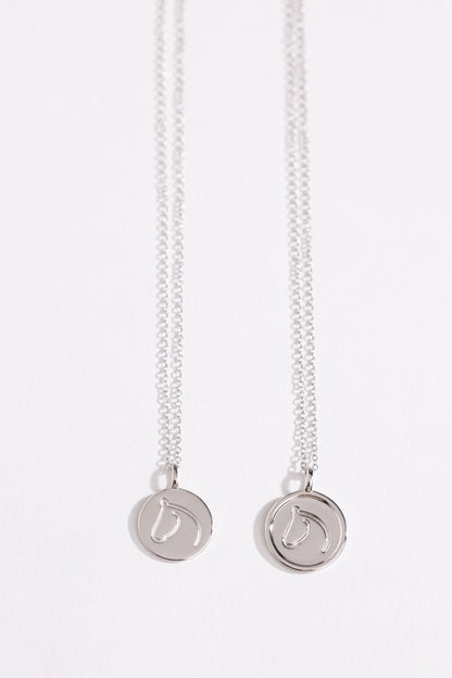 Two Sterling Silver necklaces from The Gilded Horse with round pendants on a white background.