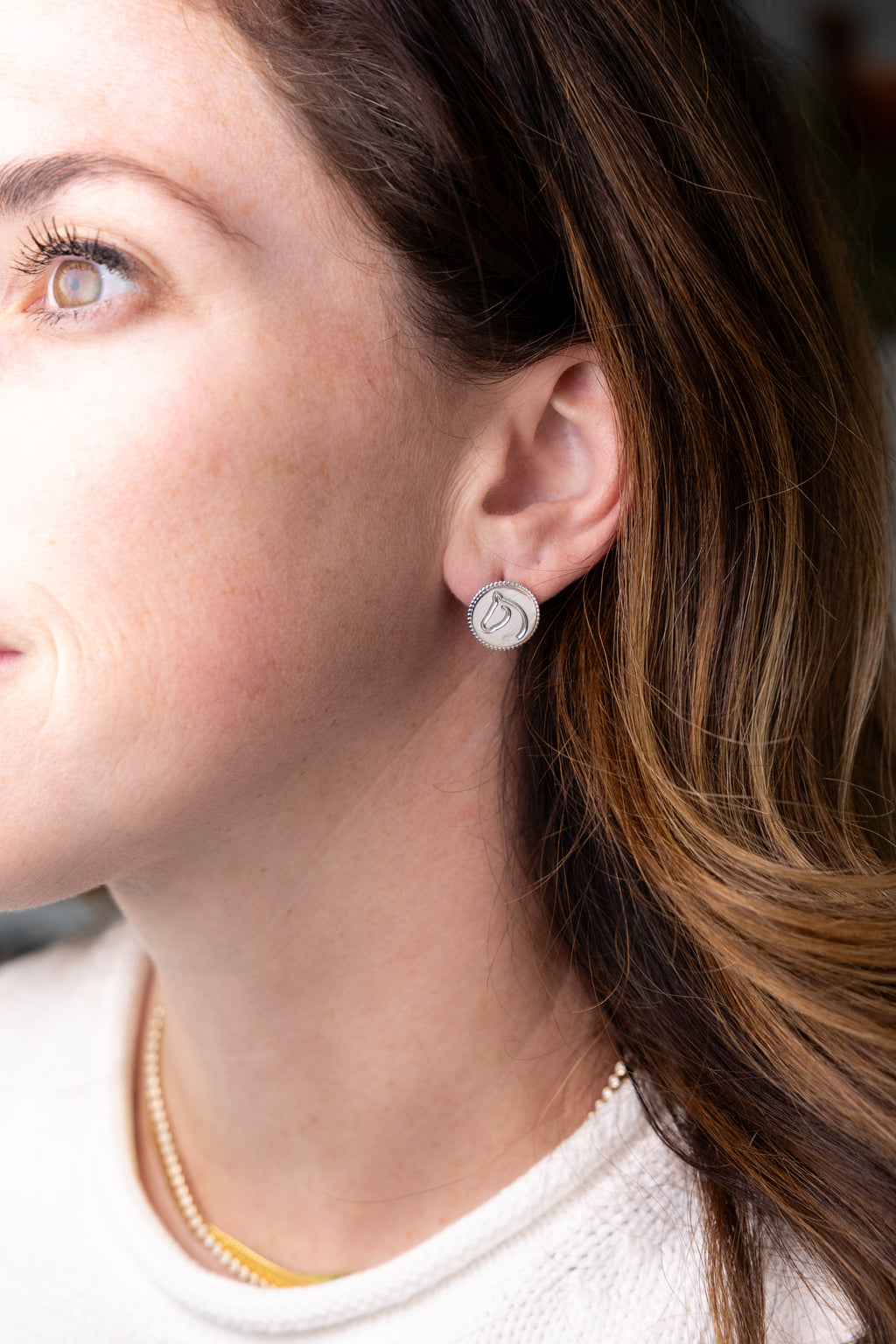 Close-up of a woman wearing a silver earring with a circular design.