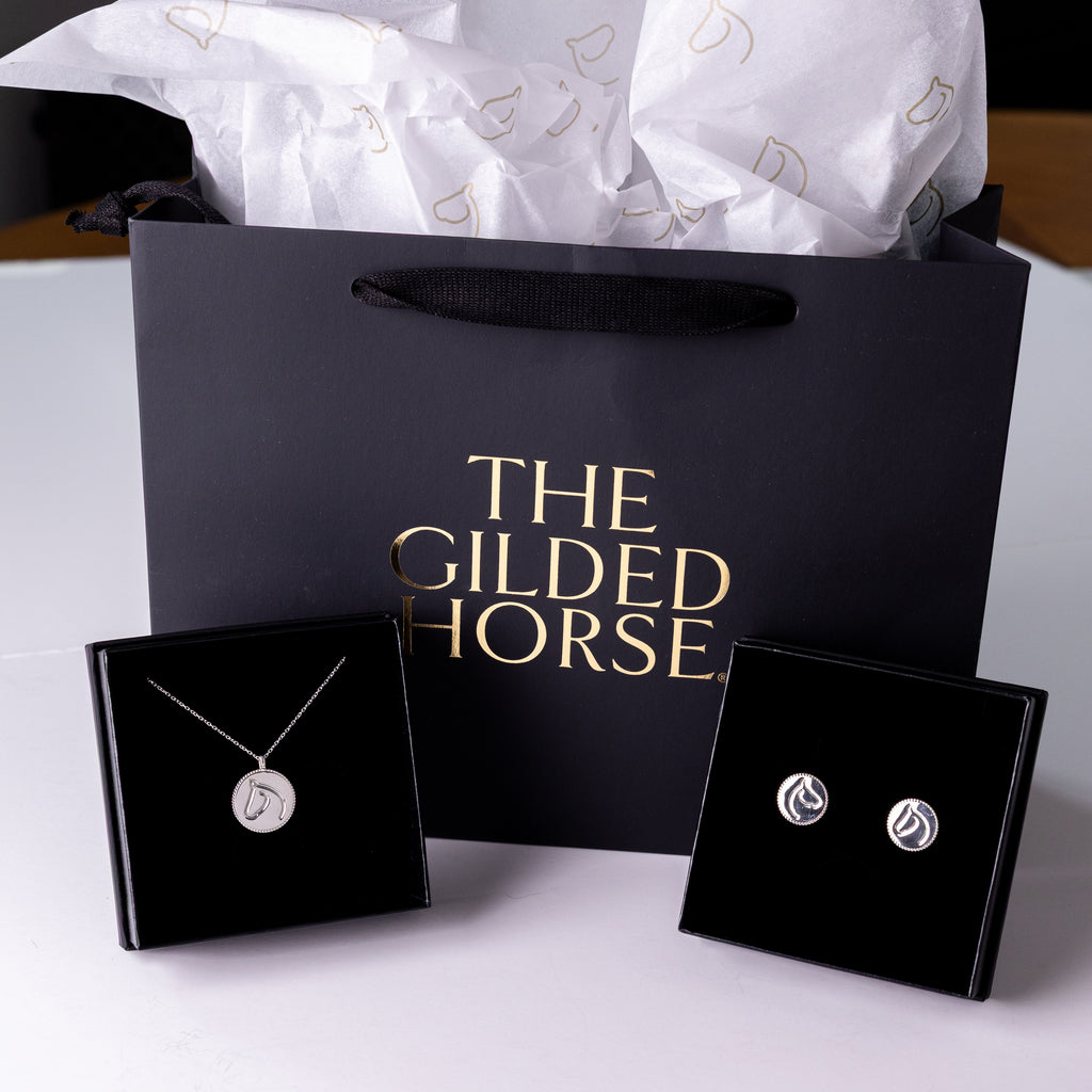 Jewelry set with 'The Gilded Horse' branding on a white surface