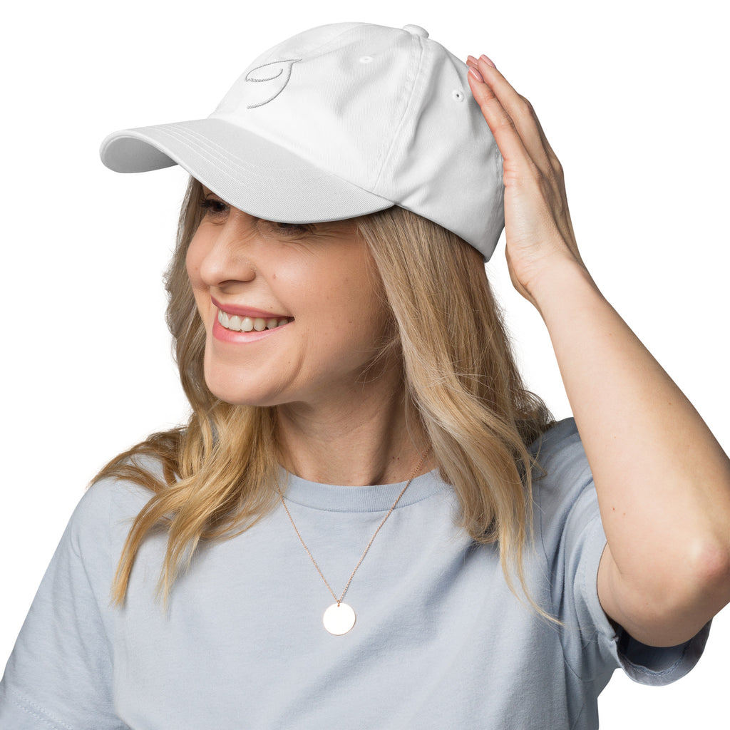 Smiling woman in a blue tee wearing The Gilded Horse white logo cap and a gold medallion necklace