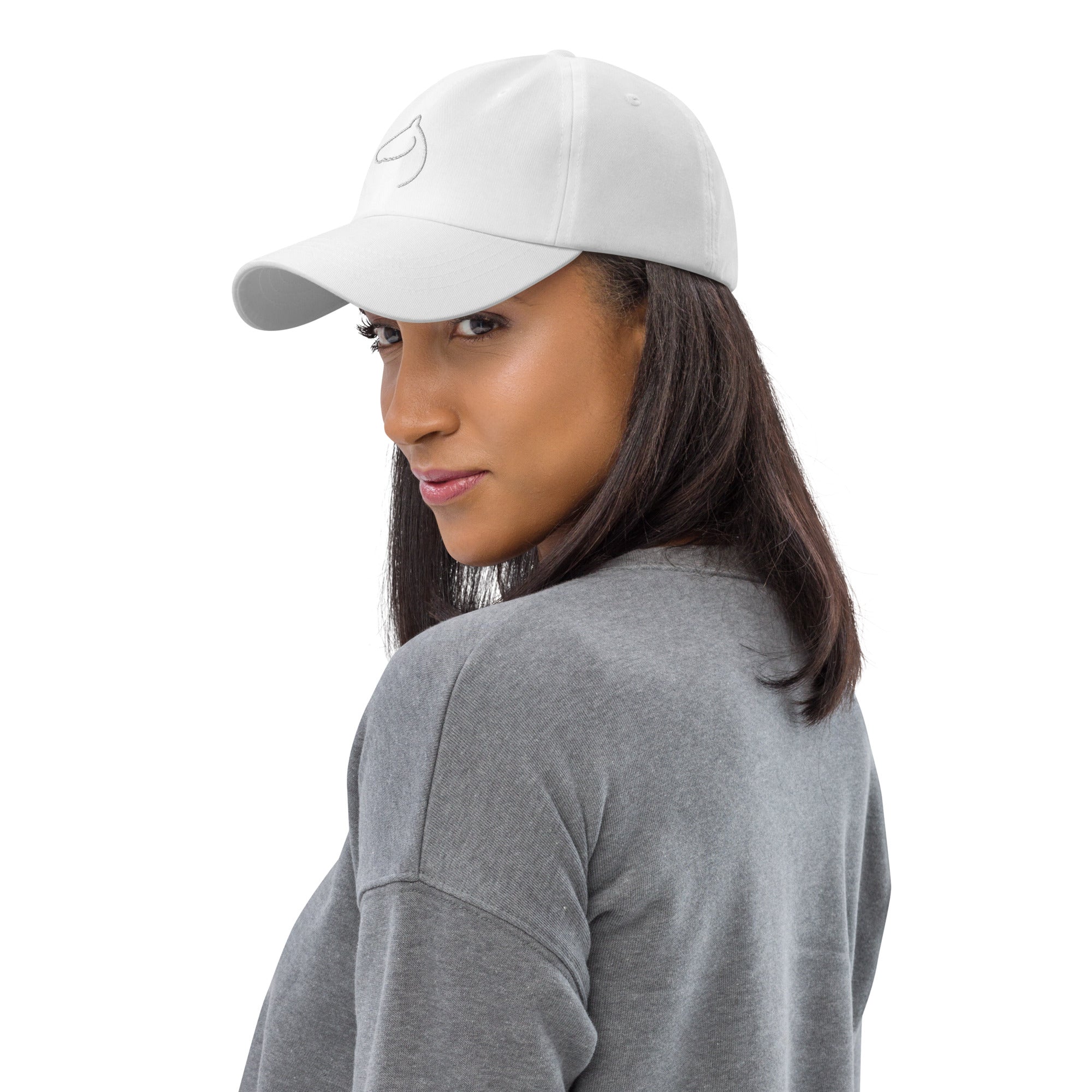 Woman glancing back while wearing a white The Gilded Horse logo cap and grey sweater