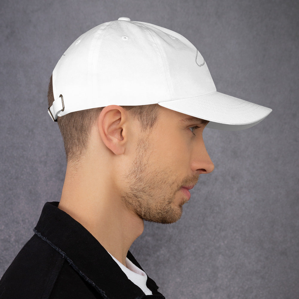 Man in profile wearing a white The Gilded Horse dad hat against a grey wall
